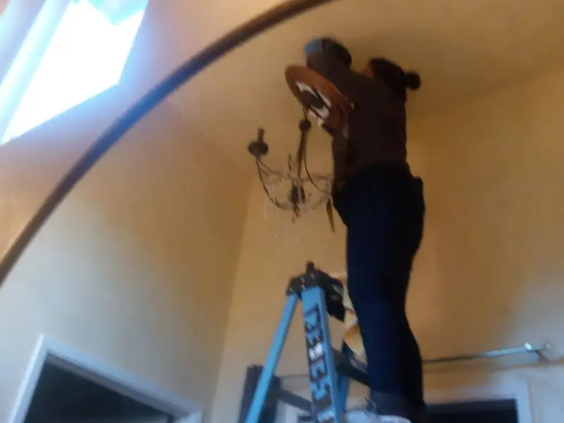 Electrician installing a chandelier in a Syracuse residence